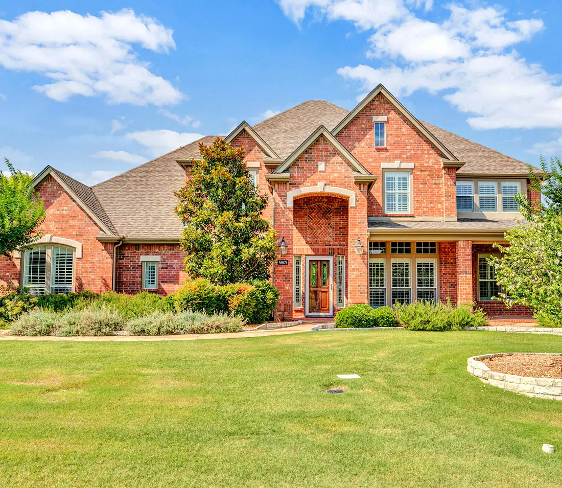 A large brick house with a lawn in front of it.