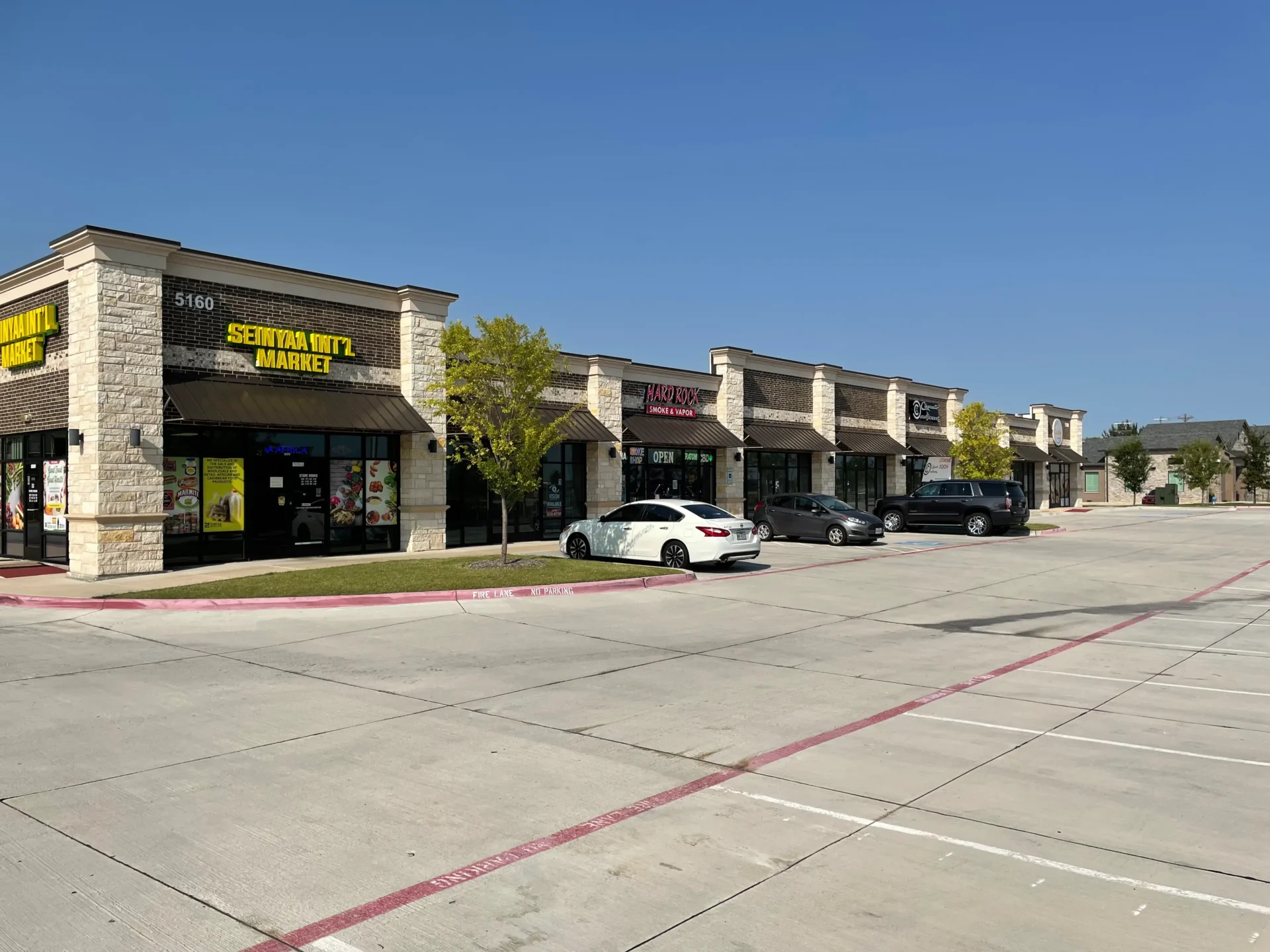 A street with many stores and cars parked on the side.